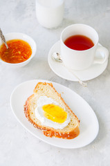 Slice of homemade challah bread with jam, glass of milk and a cup of tea on a white background. Breakfast concept.