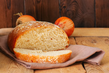 Slice of homemade onion bread on a napkin. Wooden background. Rustic style.