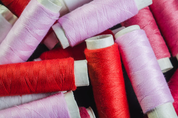 Spools of pink and red thread on black fabric