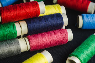 Spools of colorful threads on a black fabric