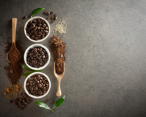 Different varieties of coffee beans with sugar and green leaf on dark vintage background. From top view