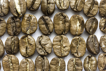 Rows of roasted coffee beans. Different shapes and different shades of brown. On a white background. Site about food, drinks, health, business.