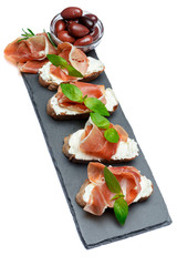 italian food with olives and prosciutto bruschettas on stone board
