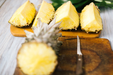 Sliced fresh pineapple on a wooden background in sunlight