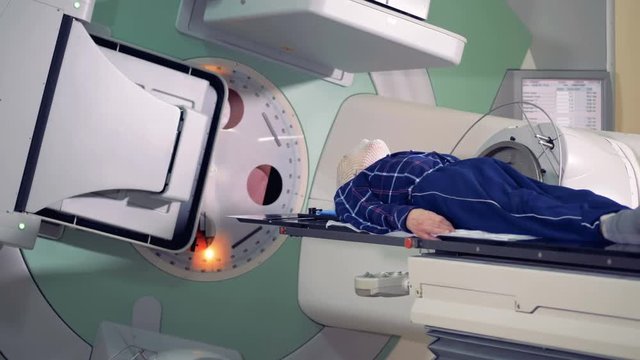 Patient lying on a table is being irradiated during treatment process