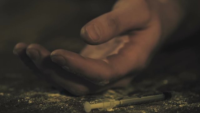 Junky hand throwing heroin syringe on floor, drug overdose danger, death risk