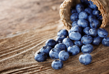 Heap of blueberries with basket on wooden background