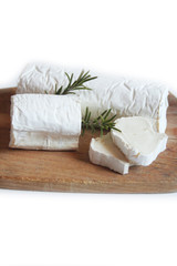 Fototapeta na wymiar Fresh goat cheese with rosemary on a wooden cutting board on white background