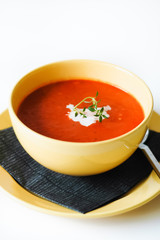 Yellow bowl filled with one serving size of homemade tomato soup for calorie counting diet or healthy, vegetarian, low carb nutrition