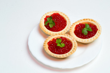 tartlets with caviar and herbs on a white plate