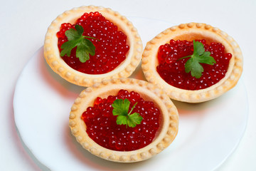 tartlets with caviar and herbs on a white plate
