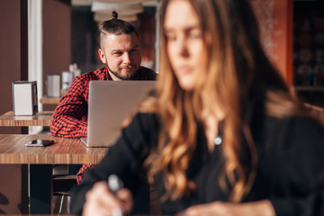 Obraz premium business young girl writing note in notebook in cafe, man with laptop on background