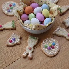 Fototapeta na wymiar Decorated Easter cookies in shape of bunny with multi colored chocolate eggs on wooden table