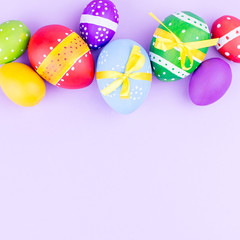 Colorful easter eggs on pastel purple background flat lay. Copy space
