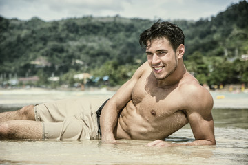 Handsome young man laying down on a beach in Phuket Island, Thailand, shirtless wearing boxer...