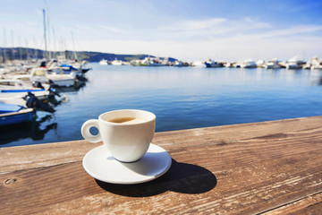 Coffee cup on a wood table over blue sky and sea background. Summer holiday concept