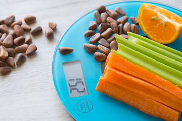 Vegetables and nuts on the scales. Calorie counting
