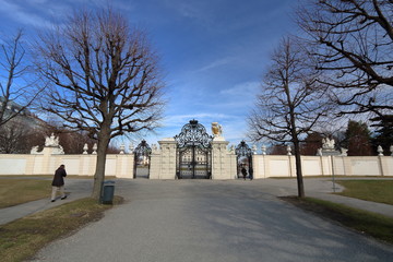 Jesienny widok głównej bramy wjazdowej do pałacu Belvedere w Wiedniu, Austria, jesienne bezlistne dzrewa, jeden turysta, piękne niebieskie niebo