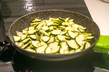 italian woman cooking zucchini in pan