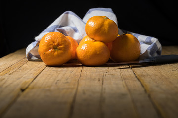 Tangerines on old wooden table with a kitchen towel