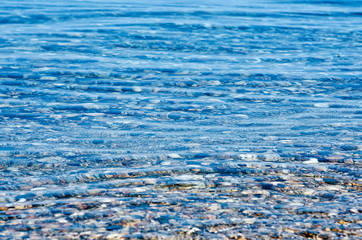 beach with pebble and turquoise water under blue sky