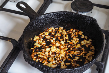 Overcooked onion in a pan. A bad kitchen. The concept of harmful food and carcinogens.
