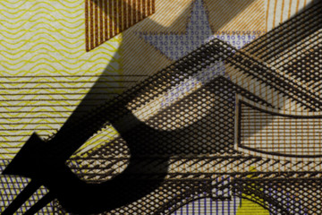A closeup photo of a part of fifty euro bill with the shadow of the bitcoin symbol falling from the side