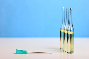 Set Ampule medical glass on white table with blue background. Syringe, needle.