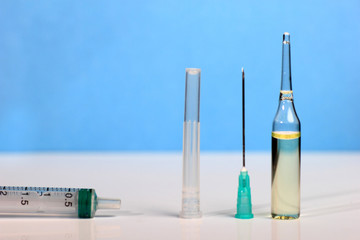 Set Ampule medical glass on white table with blue background. Syringe, needle.