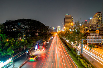 Cars light on ratchada road in night time with skyscraper building background, Bangkok, Thailand