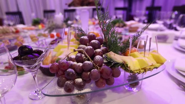 Fruit and food on the banquet table in the restaurant, pieces of pineapple and bunches of grapes on the banquet table, decoration of the banquet hall, restaurant interior