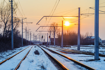 Fototapeta premium Schienen einer Bahnlinie im Schnee bei untergehender Sonne