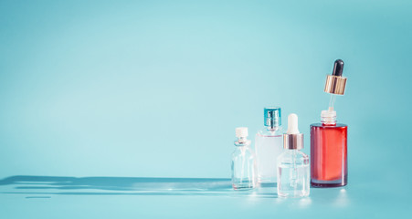 Cosmetic bottle products with liquid, pipette at blue background, front view.  Essence, toner or extract serum on table, front view. Beauty and modern skin care concept with copy space