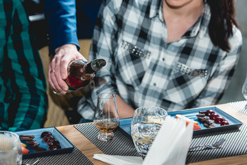 sommelier pouring whiskey into glass at hard alcohol tasting