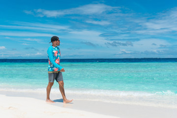 Fototapeta na wymiar Man walking on beach with transparent water of ocean in Maldives