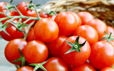 fresh cherry tomatoes in basket with water drop on wooden background
