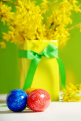 Colorful easter eggs in bowl with ribbon and flowers of golden rain tree 