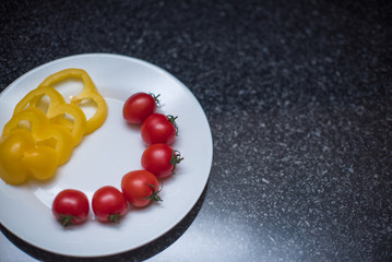 Cherry tomatoes and yellow pepper on white plate close up
