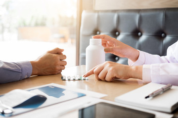  doctor hand holding tablet of drug and explain to patient in hospital room.