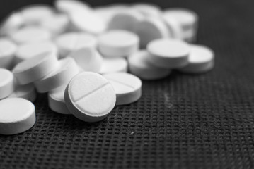 White pills on black background closeup