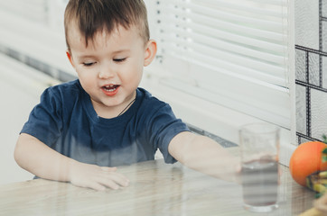 charming baby in the kitchen in the summer drink of pomegranate or cherry juice red color