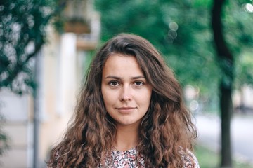 Naklejka premium portrait of a charming curly-haired girl on a walk in the city.