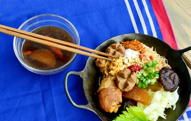 dried chicken noodle Thai style  in old wok with soup in glass bowl