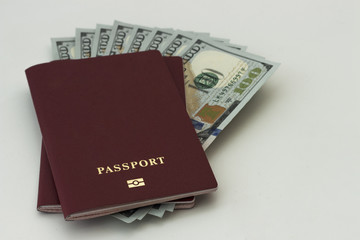 Two red passports and one hundred dollars bills inside. Isolated, close-up.