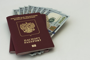 Fototapeta premium Two red Russian passports and one hundred dollar notes inside. Isolated on white background.