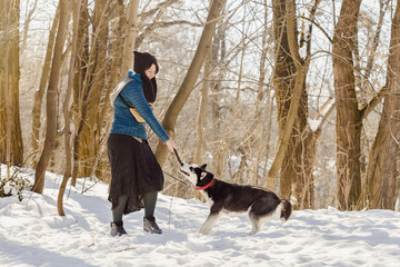 Fototapeta na wymiar Woman playing with her husky dog on the snow
