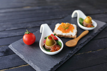 Appetizer plate with red caviar on crispy biscuit and green olives filled with pickles and wrapped...