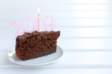 festive event 2019/ piece of chocolate cake with figures and a lighted candle
