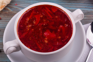 Red borsch in a white cup, is served with sour cream