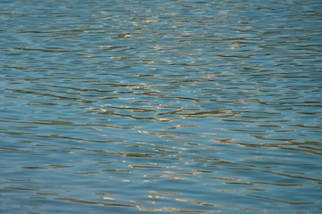 Texture of blue clear river water with reflections of clouds